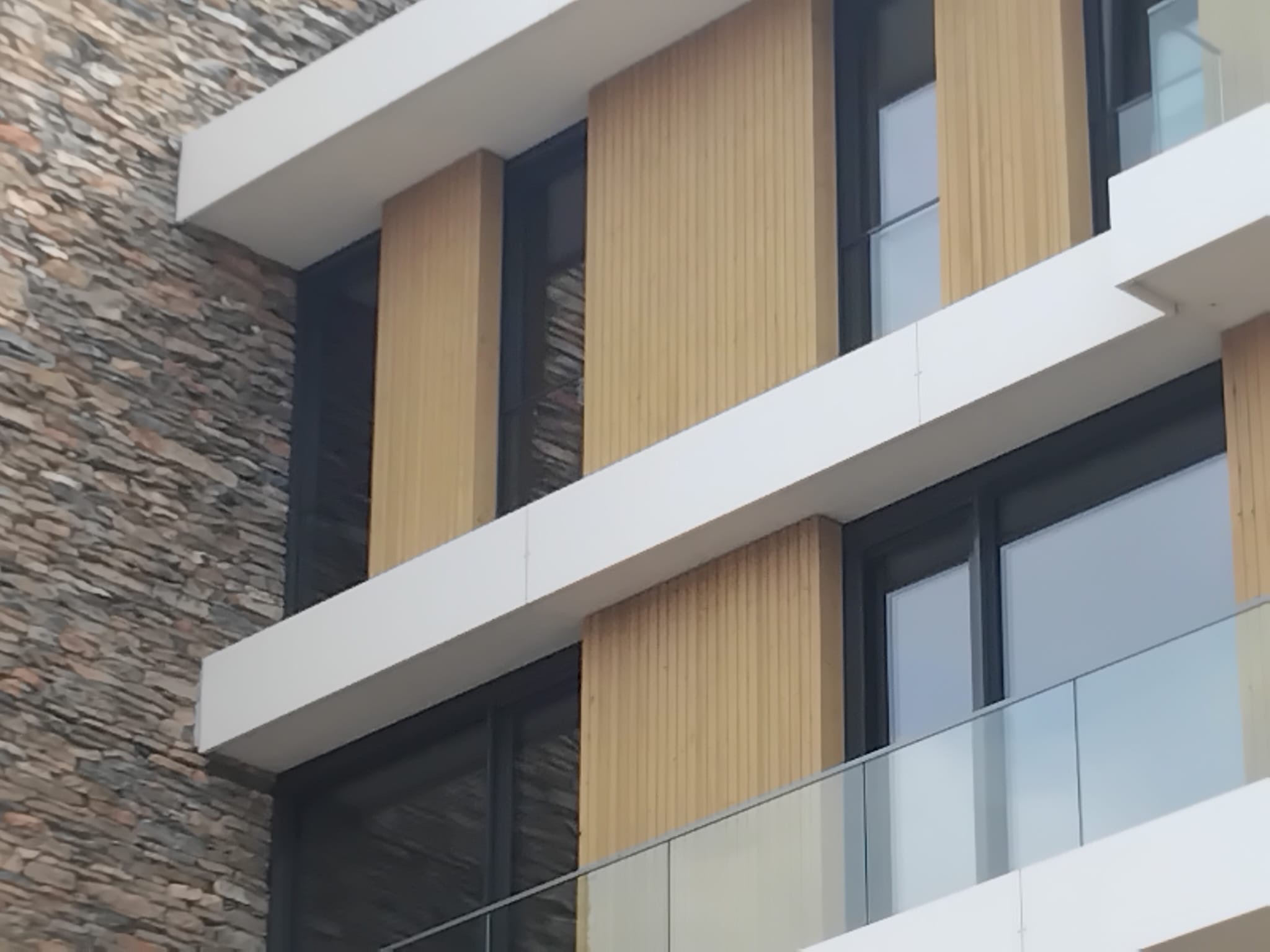 Afgewerkte gevel met gebalanceerde materialen, balkons en houtaccenten
